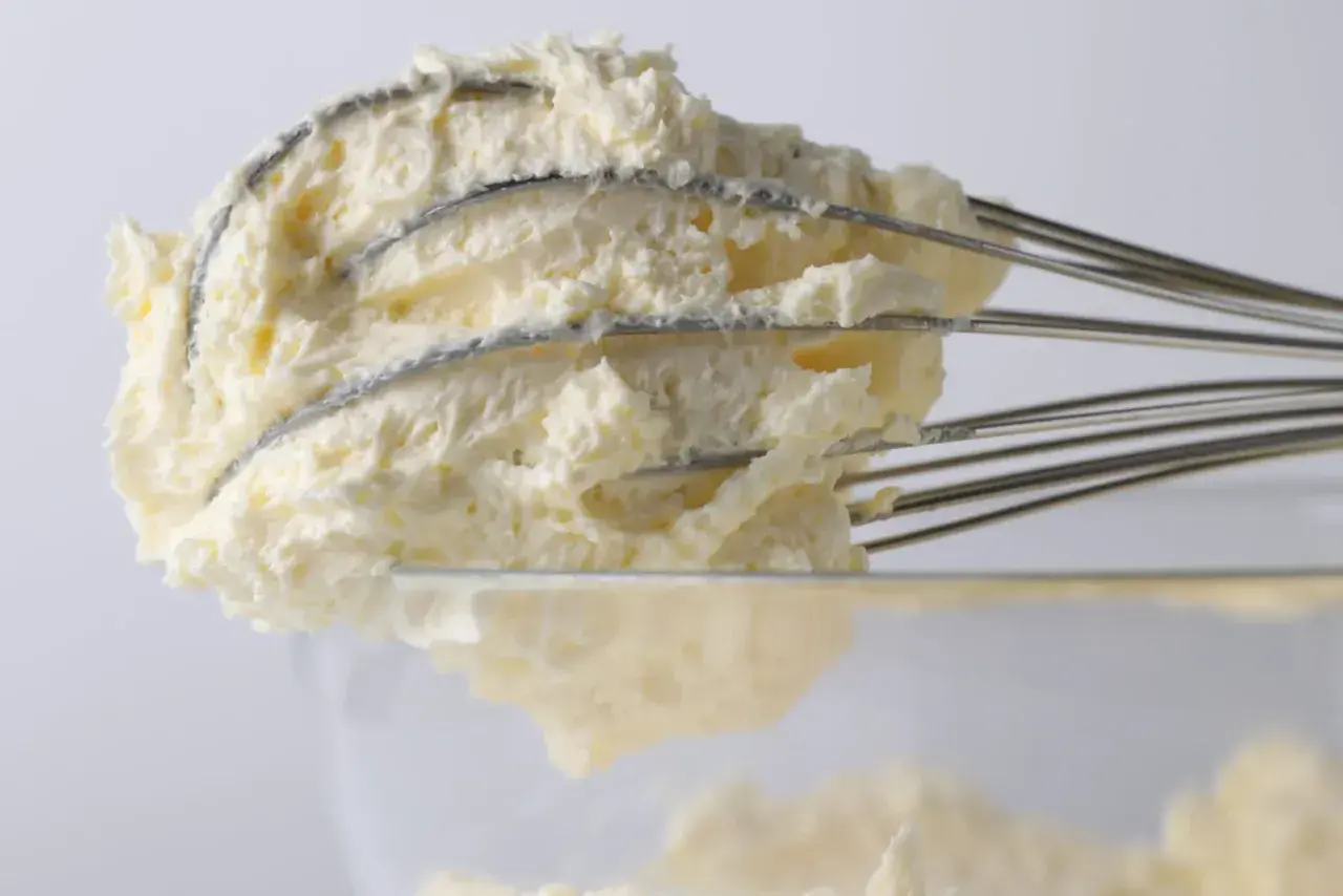 Krem z mascarpone na drucianej trzepaczce miksera, widok z bliska.