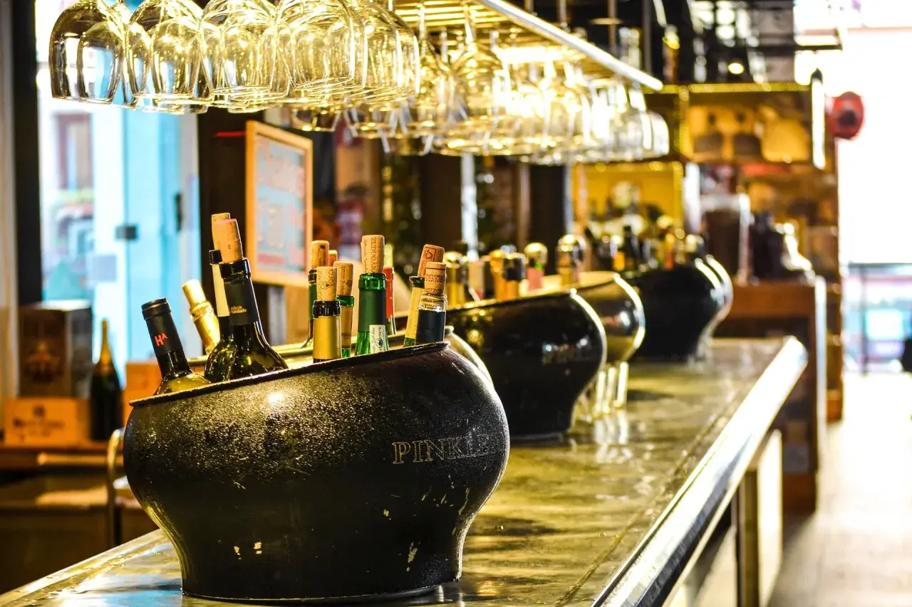 Butelki w wiaderku na lód, w tle kieliszki i inne alkohole. Zastanawiasz się, jaki alkohol ma najmniej kalorii?