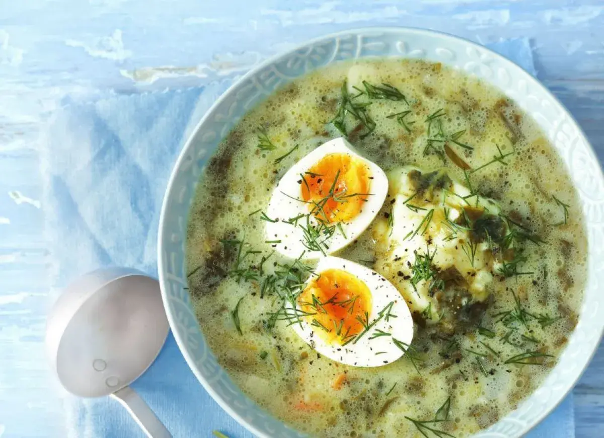 Zupa szczawiowa z jajkiem i koperkiem w misce, obok chochla.
