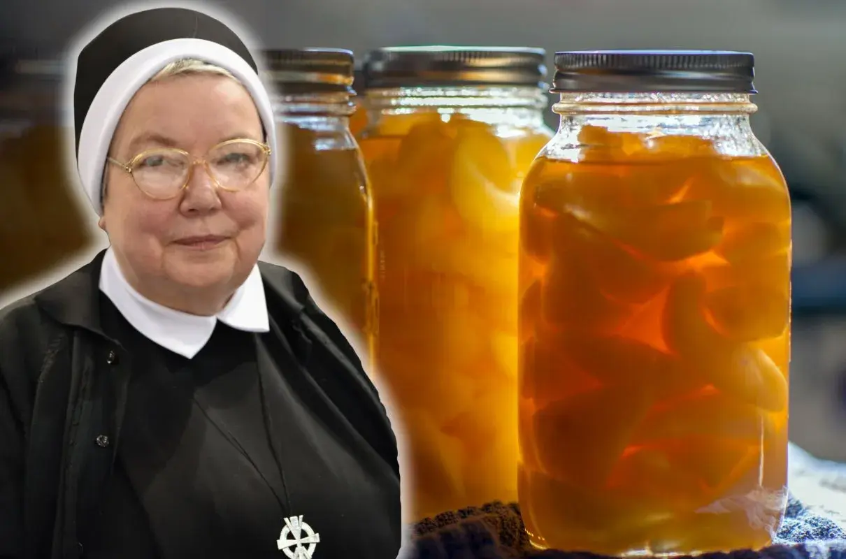 Zakonnica obok słoików z gruszkami w zalewie.