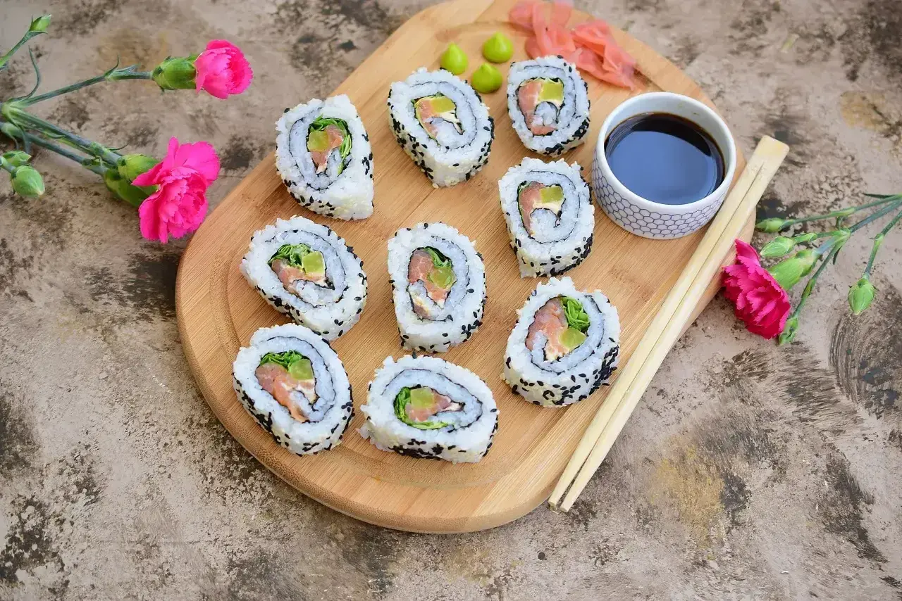 California sushi z łososiem i awokado, posypane czarnym sezamem, podane z sosem sojowym i wasabi.
