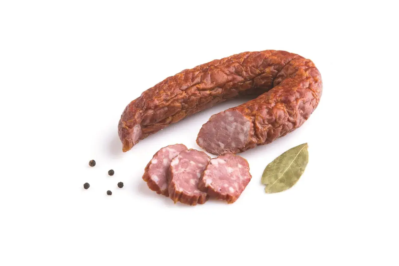 Kiełbasa jałowcowa w całości i w plasterkach, z ziarnami pieprzu i liściem laurowym.