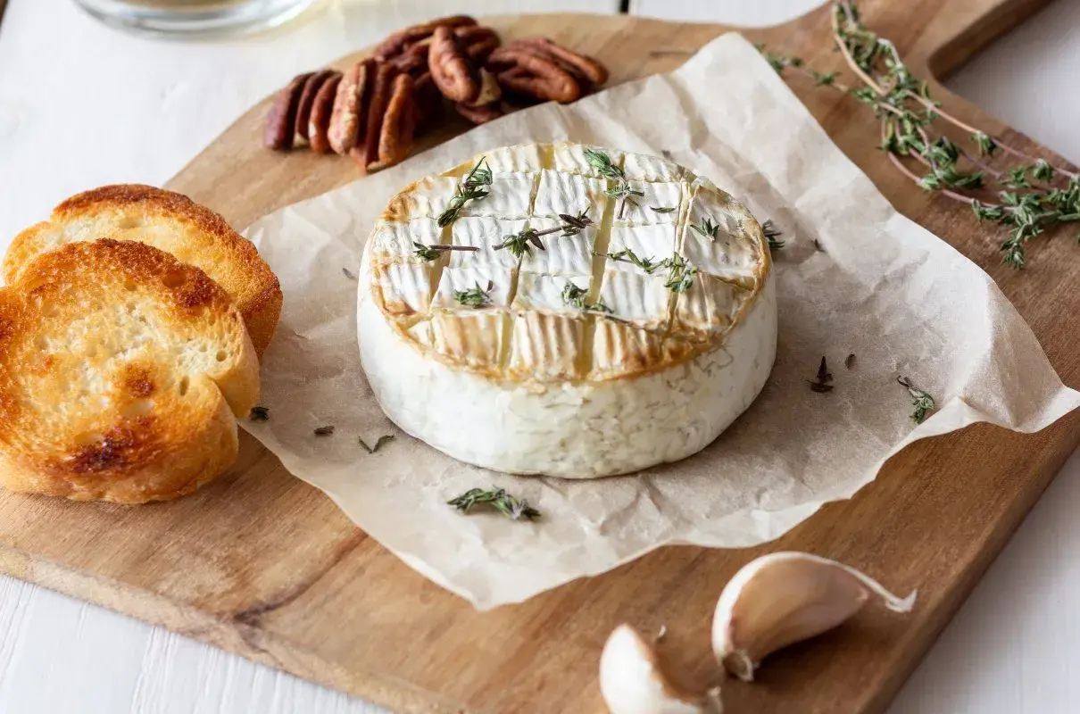 Pyszny, pieczony camembert z tymiankiem, podany z grzankami, orzechami pekan i czosnkiem. Idealny na przekąskę.