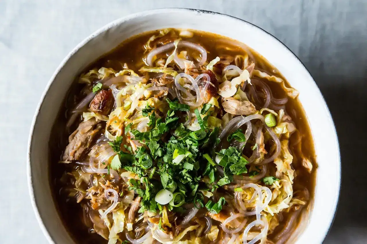 Miseczka aromatycznego tantanmen z makaronem, kapustą i zieloną cebulką, posypana świeżą kolendrą.