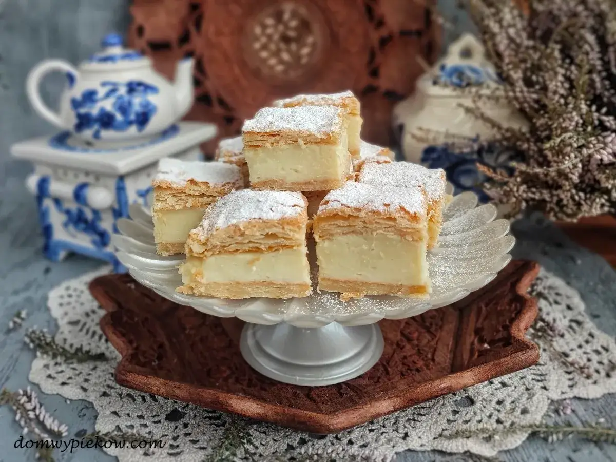Pyszne napoleonki, jak z przepisu babci, na paterze. Kremowe, puszyste, posypane cukrem pudrem.