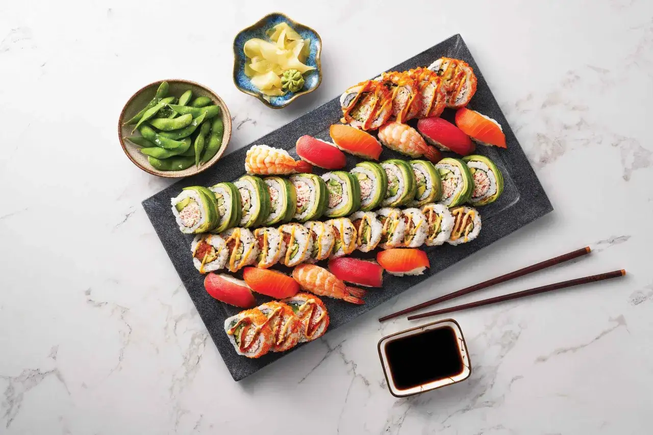 Talerz pełen różnorodnych roladek sushi, nigiri z łososiem i krewetką, miseczka edamame i marynowanego imbiru – idealny zestaw, by zacząć ucztę co do sushi.