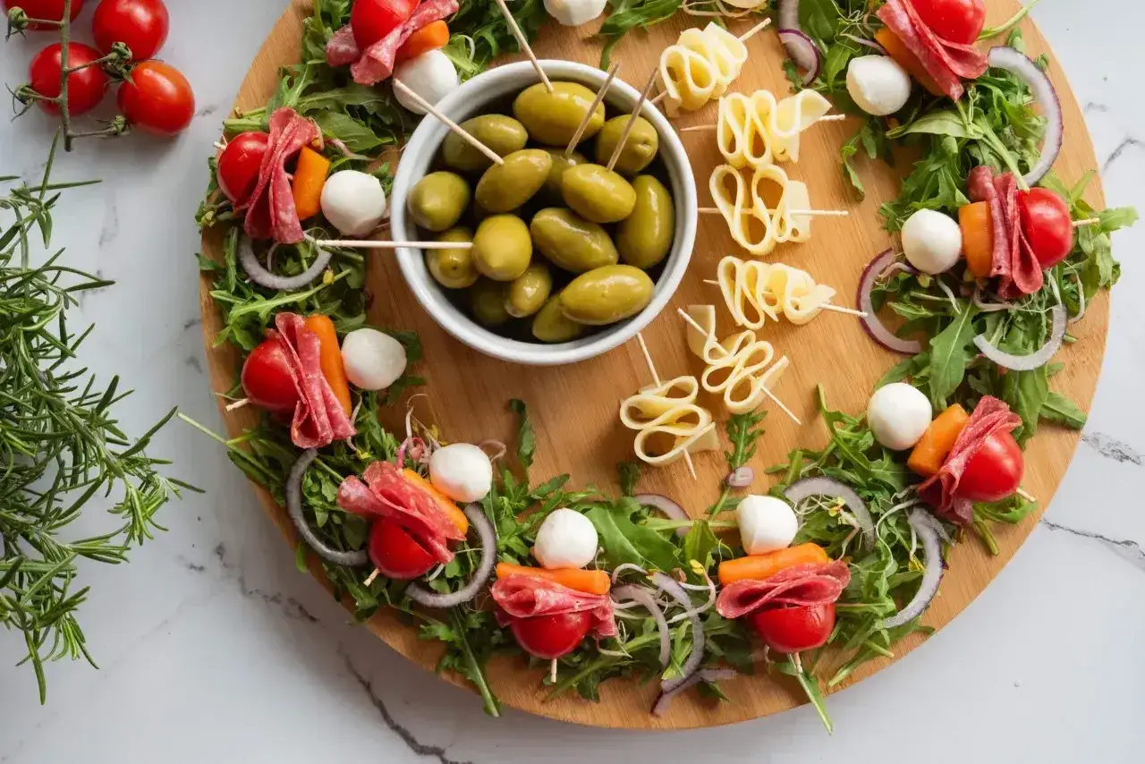 Szybkie sałatki imprezowe na patyczkach: pomidorki, salami, kulki mozzarelli, marchewka, oliwki i ser.