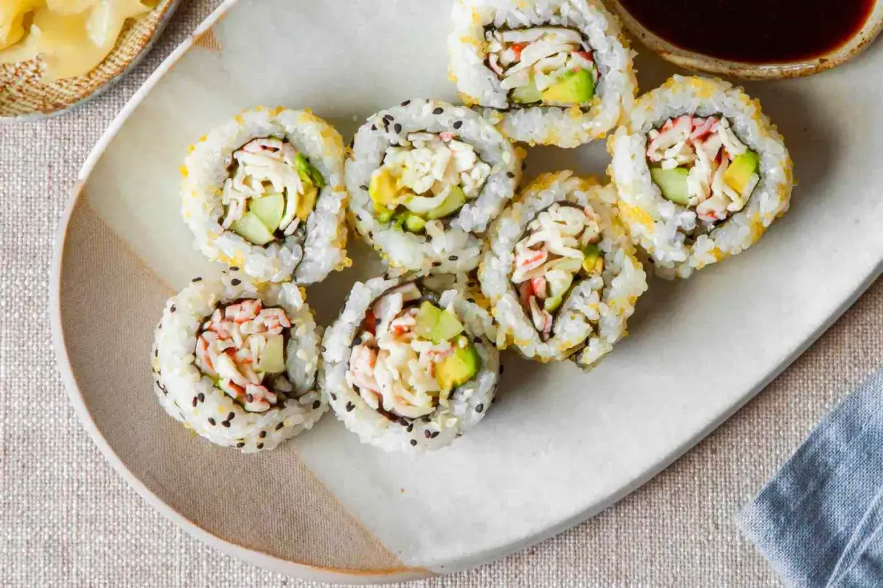 Siedem kawałków california sushi z awokado, ogórkiem i paluszkami krabowymi, posypane sezamem i ikrą.