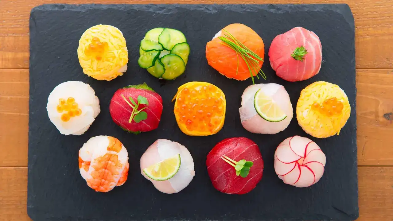 Kolorowe sushi na czarnej desce. Różne rodzaje, od łososia po krewetki. Idealne dla tych, którzy liczą sushi kcal.