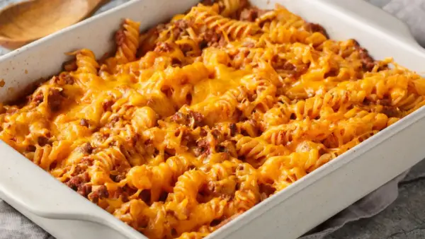 Zapiekanka makaronowa z mięsem mielonym w sosie śmietanowym, pokryta roztopionym, ciągnącym się serem cheddar.